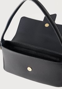 Μαύρη υφασμάτινη τσάντα ώμου με ανοιχτό καπάκι, που αποκαλύπτει το μαύρο εσωτερικό ύφασμα με εκτύπωση "Armani Exchange" και χρυσές μαγνητικές κλειδαριές.