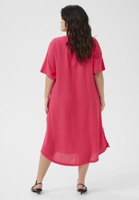 Pink, loose-fitting dress with short sleeves and a rounded hem. Made of lightweight fabric, features a simple, unembellished design.