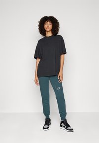 Nike Sportswear CLUB SHINE PANTS - Teplákové kalhoty - deep jungle