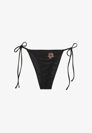 Czarne doły od bikini z troczkami po bokach oraz małą różową dekoracją z kryształków w kształcie kwiatu z przodu po lewej stronie.