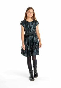 Robe plissée bleu foncé avec des manches courtes et une taille élastique, associée à des collants noirs et des bottes à lacets. Le tissu a une finition brillante.