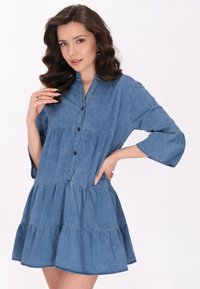 Denim-paitakleid mit geknöpften Vorderseite, gestuften Rüschensaum und Dreiviertelärmeln. Hellblaue Farbe und weiche Textur.