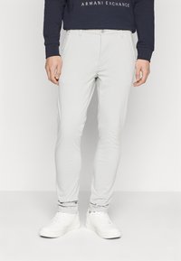 Pantaloni slim-fit gri deschis, cu o textură netedă, cu închidere cu nasture și design cu cinci buzunare, asortați cu adidași albi.