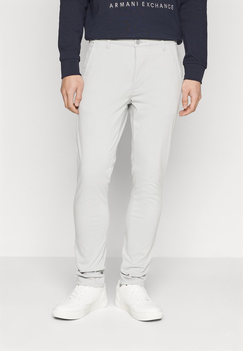 Pantaloni slim-fit gri deschis, cu o textură netedă, cu închidere cu nasture și design cu cinci buzunare, asortați cu adidași albi.