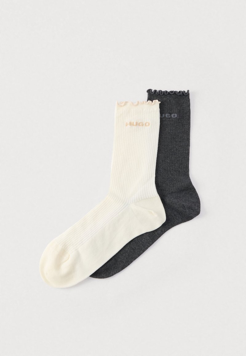 Dos pares de calcetines acanalados: uno en color blanco hueso con bordes ondulados y logotipo, y el otro en gris oscuro con un diseño simple y logotipo.