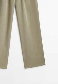 Pantalon beige à jambe droite posé à plat, montrant la moitié inférieure des deux jambes sur fond blanc.