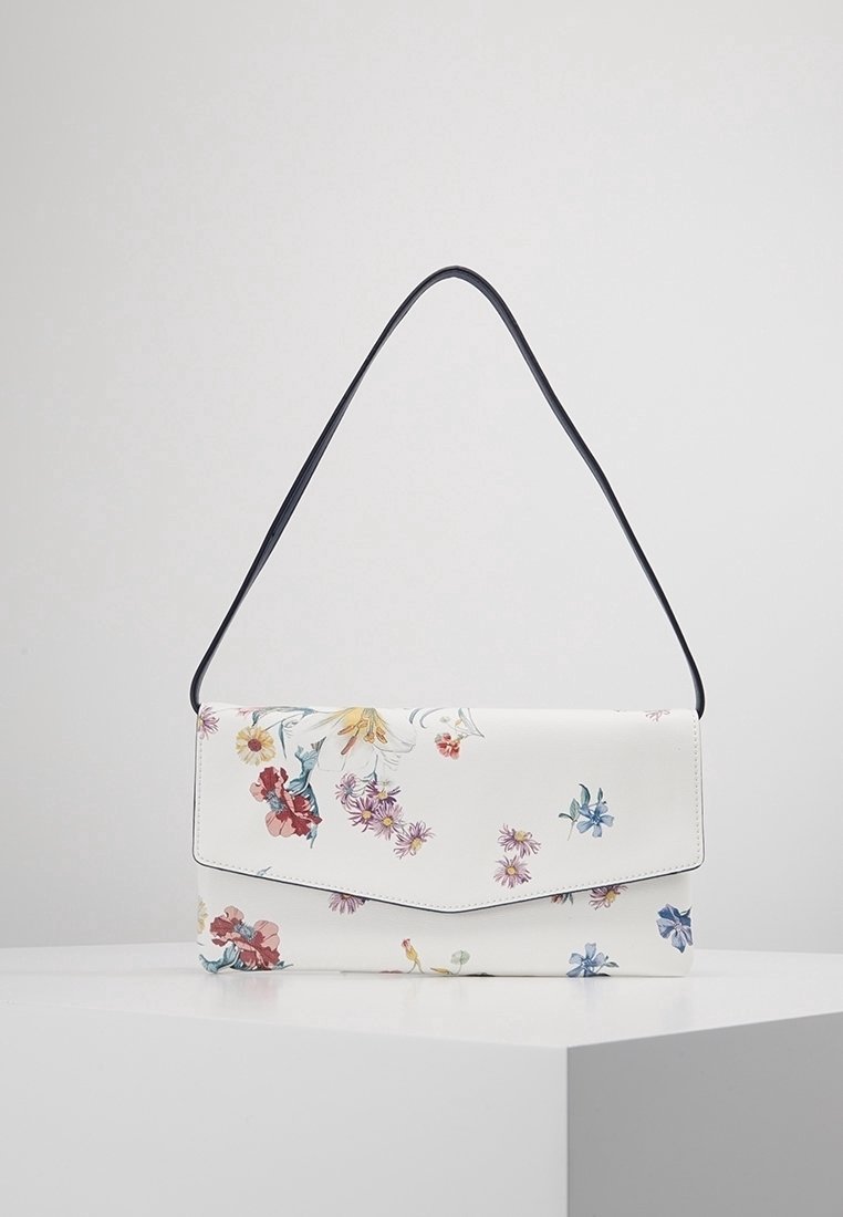 Hvid blomster skuldertaske med en sort rem. Har en klaplukning og livlige blomster mønstre i røde, blå og gule nuancer. Glat tekstur.