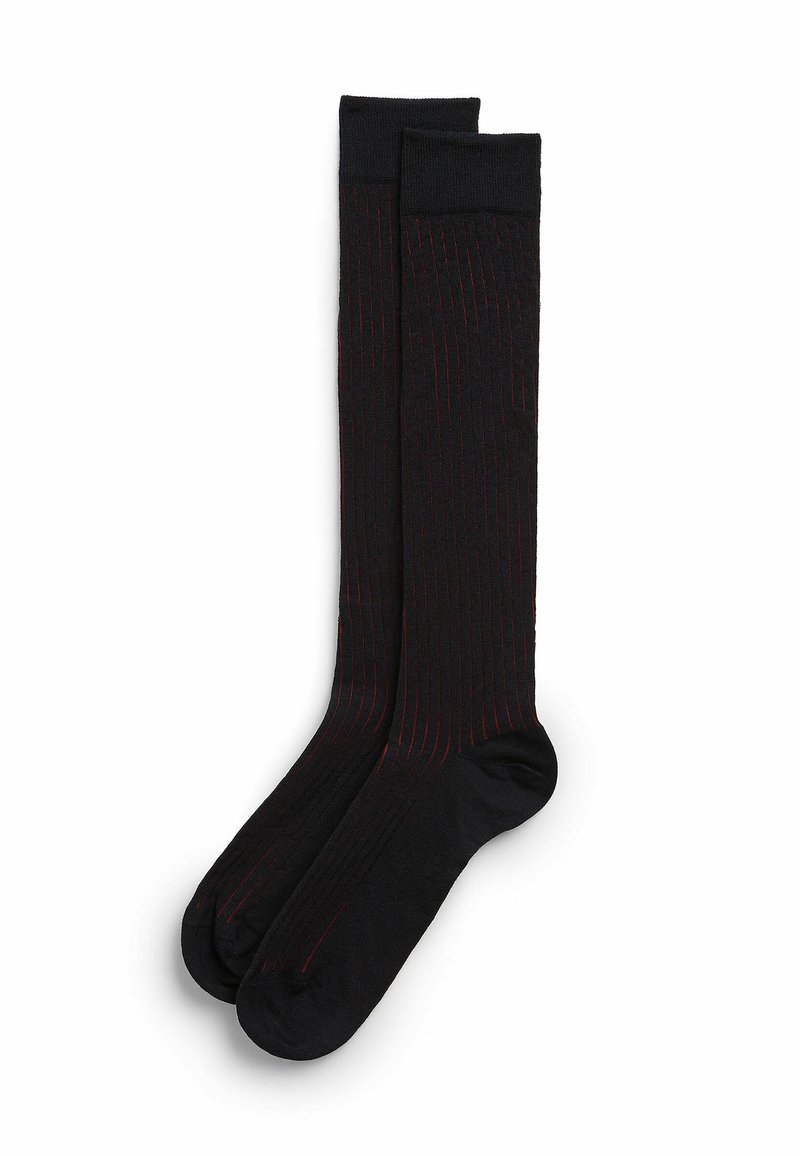 Czarne skarpetki do kolan z subtelnymi czerwonymi paskami, żebrowana struktura oraz wzmocnione obszary palców i pięt dla zwiększenia trwałości.