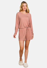 Roze gestippelde lounge-outfit bestaande uit een langarmige top met een geknoopt voorpand en bijpassende shorts met een elastische tailleband. Zachte textuur.
