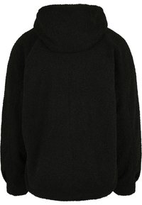 Veste en polaire noire avec une finition douce et texturée. Elle dispose d'une capuche et de manches tombantes, avec des poignets élastiques pour un ajustement décontracté.