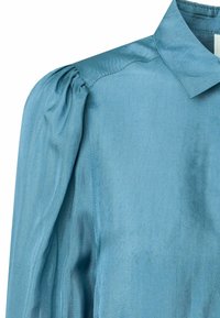 Blusa azzurro chiaro con finitura testurizzata, caratterizzata da un colletto classico e maniche a sbuffo per una maggiore dimensione.