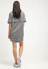 Grå sweatshirtklänning med korta ärmar, rundad nederkant och kontrasterande marinblå muddar. I hop med svartvita sneakers. Slät textur.