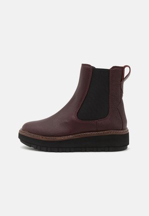 Bottines en cuir bourgogne avec panneaux élastiques latéraux, semelle noire contrastante et détail de couture subtil. Bout arrondi et tirant à l'arrière.
