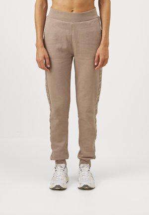 Beige joggings med en tapered ben, elastisk talje og sidestriber med et subtilt mønster. Lavet af blødt, struktureret stof.