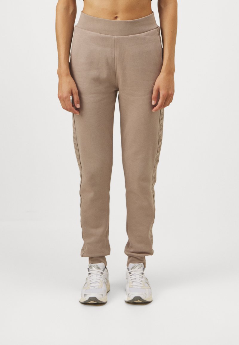 Beige joggings med en tapered ben, elastisk talje og sidestriber med et subtilt mønster. Lavet af blødt, struktureret stof.