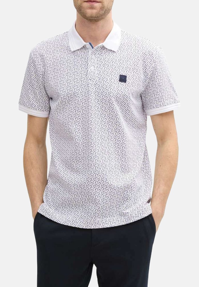 Polo shirt à manches courtes en blanc avec un motif noir éparpillé, arborant un col contrasté et un petit logo sur la poitrine.