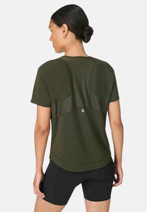 Olivengroen sport T-shirt met een geribbelde achterkant en een afgeronde zoom, gecombineerd met zwarte shorts. Materiaal lijkt lichtgewicht en ademend te zijn.