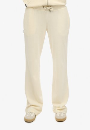 Kremowe spodnie dresowe z miękkiego materiału o luźnym kroju, wyposażone w regulowany ściągacz w talii oraz boczne kieszenie.