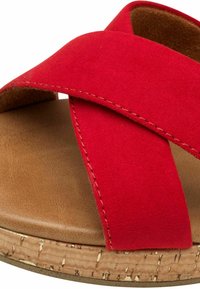 Sandalia deslizante de ante rojo con correas entrecruzadas, una suela intermedia de corcho y una plantilla marrón suave. Detalle de costura a lo largo de los bordes de las correas.