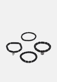 Fire sorte svarte armbånd med ulike design: ett med et korsanheng, et annet med en teksturert mønster, og runde, glatte perler på to andre.