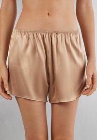 Satin beige shorts met een elastische tailleband, met een slanke, gladde textuur en een losse pasvorm, die tot halverwege de dij reiken.