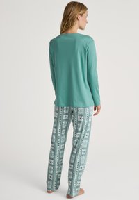 Maglia a maniche lunghe verde menta e pantaloni da pigiama con motivo fantasia caratterizzati da design turchesi e bianchi con motivi geometrici e accenti floreali.