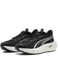 Chaussures de sport noires avec une tige en maille texturée, une semelle intermédiaire blanche et de jolis accents argentés sur le côté et les lacets.