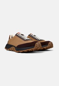 Sneakers marroni e beige con superficie texture, lacci bianchi e suole in gomma marrone dotate di un motivo di trazione. Accentuati con un marchio rosso.