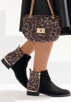 Schwarze Wildlederstiefeletten mit Akzenten im Leopardenmuster und goldenen Reißverschlussdetails; kombiniert mit einer Handtasche im Leopardenmuster, die einen goldenen Kettenriemen hat.