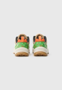 Atlétikai cipő hátulnézete: zöld mintás felsőrész, narancssárga és bézs részletek, fekete szegély, gumi talp tapadással.