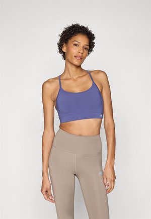Lilla idretts-BH med tynne stropper og glatt tekstur, kombinert med høyt midje-beige leggings med en liten logo.