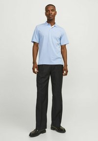 Világoskék pólóing fehér gallérral, rövid ujjú, apró logóval, fekete nadrággal és fekete cipővel párosítva.