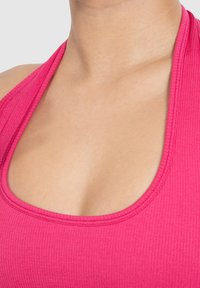 Top de tirantes acanalado rosa con escote redondeado y tirantes estilo halter, que presenta una tela texturizada y un diseño ajustado.