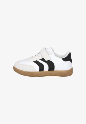 Zapatilla blanca con rayas negras, cierre de cordones, una tira de velcro y suela marrón texturizada, vista desde el lado exterior.