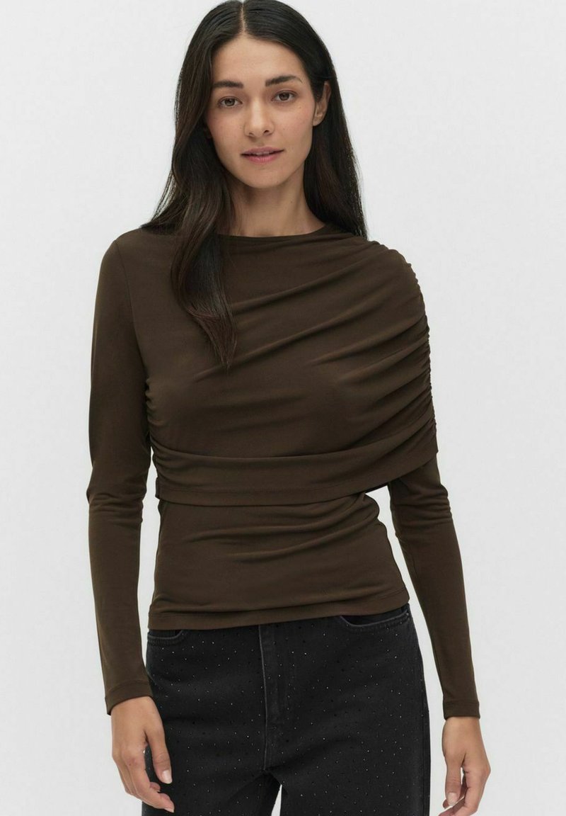 Ruskea pitkähihainen paita, jossa on rypytetty kangas yksityiskohta kauluksen ympärillä, sileä pinta ja kiinteä siluetti, yhdistetty tummiin, pisteellisiin farkkuihin.