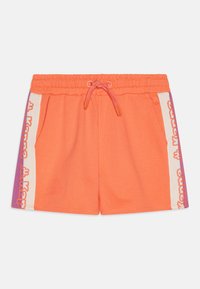 Shorts en coton orange avec une taille élastique et un cordon de serrage. Présence de panneaux latéraux blancs avec un logo Kappa violet. Texture douce, design sportif.