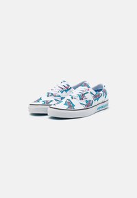 Baskets en toile avec une base blanche, décorées de motifs de requins colorés et d'accents. Comprend des lacets et une semelle en caoutchouc.