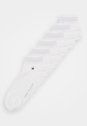 Meias brancas até ao tornozelo em mistura de algodão. Apresentam um punho canelado e um pequeno logotipo com ressaltos em vermelho, branco e azul perto do tornozelo.