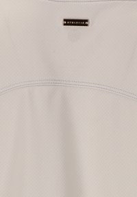 Hellegraues Sportoberteil mit strukturiertem Stoff, Rundhalsausschnitt und kontrastierenden Nähten. Besitzt ein kleines metallisches Etikett mit dem Markennamen.