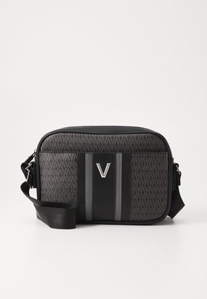 Kompakti musta olkalaukku, jossa on teksturoitu geometrinen kuvio, säädettävä olkahihna ja keskellä etupaneelia hopeinen "V"-logo.