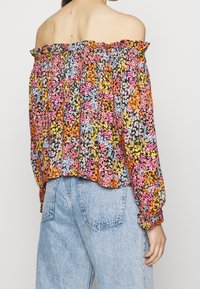 Off-shoulder bloes met bloemenpatroon en elastische halslijn, met een kleurig patroon van roze, geel, blauw en zwart op een lichtgewicht stof.