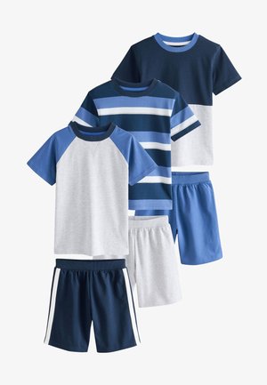 Tri bosa dječaka stoje s leđima okrenutima, nose plave i sive majice kratkih rukava i odgovarajuće kratke hlače na neutralnoj pozadini.