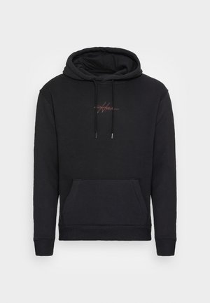 Sudadera negra con capucha, bolsillo frontal tipo canguro y cordones, con un pequeño texto rojo en cursiva centrado en el pecho.
