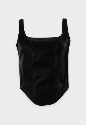 Mujer con top negro sin mangas ajustado y pantalones negros de pierna ancha con cortes, sosteniendo un bolso negro de cuero sobre el hombro.