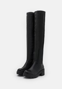 Botas de cuero negro hasta la rodilla con un acabado suave, punteras redondeadas, suelas gruesas y cremalleras laterales para facilitar su uso.
