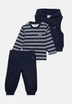 Ensemble bébé bleu marine trois pièces avec tee-shirt à manches longues rayé, pantalon uni et gilet sans manches à capuche, tous marqués du logo "BOSS".