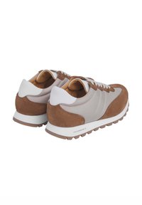 Zapatillas marrones y grises con parte superior de ante y tejido, acentos blancos, cuello acolchado y suela de goma texturizada. Diseño ligero y deportivo.