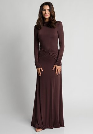 Długa sukienka z długim rękawem w głębokim brązowym kolorze. Posiada marszczenie w talii oraz dopasowane rękawy z delikatnym marszczeniem.
