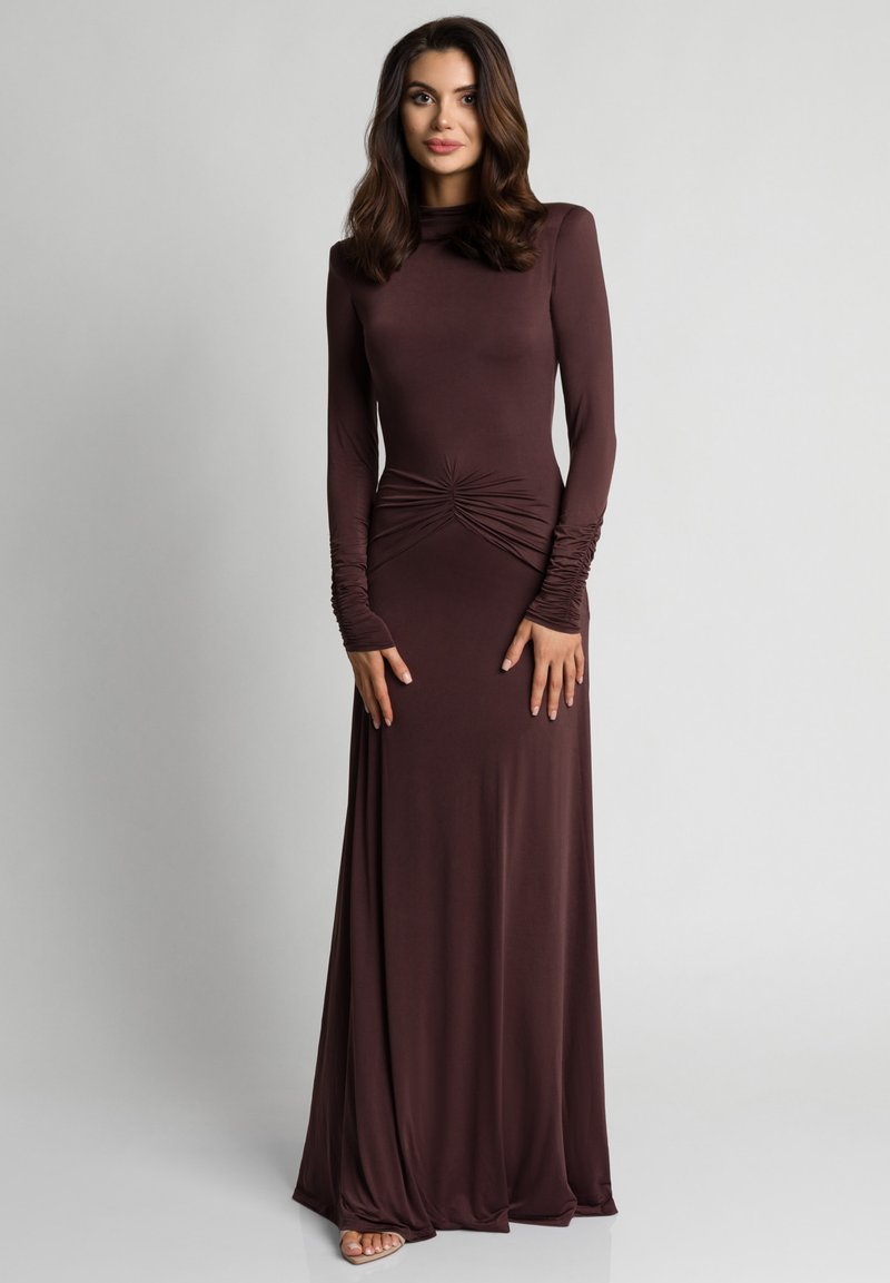 Długa sukienka z długim rękawem w głębokim brązowym kolorze. Posiada marszczenie w talii oraz dopasowane rękawy z delikatnym marszczeniem.