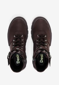 Smeđe kožne čizme s dizajnom na vezanje, metalnim okošcima, bočnim zatvaračem i podstavljenim ovratnikom. Unutrašnjost sadrži logo na podstavljenoj ulošci.